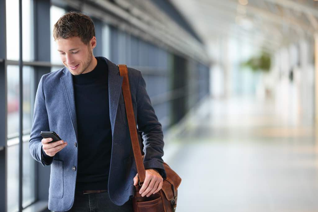 Geschäftsreise: Mann mit Smartphone am Flughafen