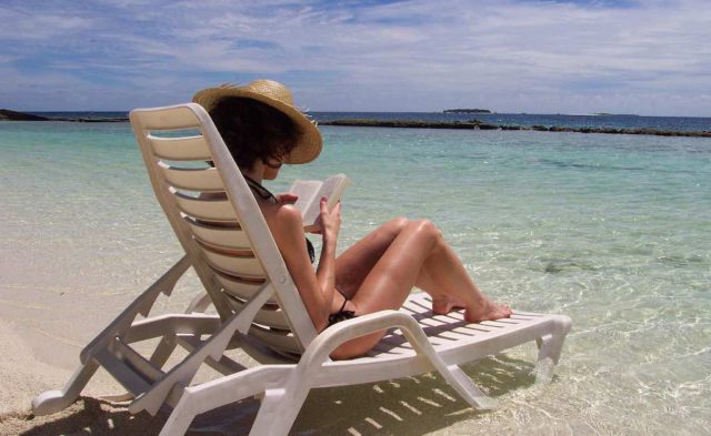 Fernreise: Frau auf Sonnenliege am Strand auf den Malediven