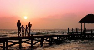 Wohin reisen Urlauber am liebsten? Urlauber: Familie auf einem Bootssteg bei Sonnenuntergang