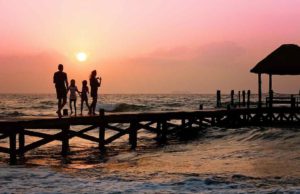 Wohin reisen Urlauber am liebsten? Urlauber: Familie auf einem Bootssteg bei Sonnenuntergang