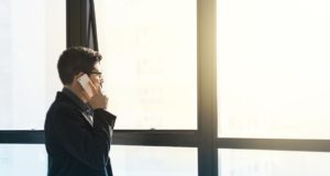 Wenn falscher Chef echte Firma abzockt Mann steht am Fenster und ruft eine Firma an