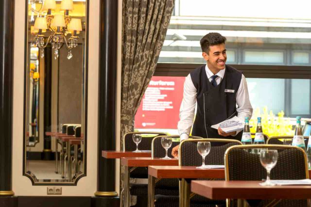 Mit entspannter Atmosphäre, exzellentem Service und freundlichem Personal punktet die Hotellerie bei iGästen: Kellner beim decken von Tischen in einem Hotel