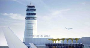 Sommerflugplan mit 190 Flugzielen ab Wien Flughafen Wien mit dem Tower im Hintergrund und vorne ist das Heck eines Flugzeugs zu sehen. Am Himmel fliegt ein Jete über den Flughafen Wien