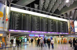 Flug verspätet? Was Sie dann tun sollten! Flug verspätet? Entschädigung bei Flugverspätung können sofort geltend gemacht werden. Passagiere vor Anzeigetafeln am Flughafen