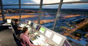 Pünktlichkeit bei Airlines nimmt wieder zu Fluglotsen im Tower sitzen vor Bildschirmen und kontrollieren die Flugverkehr am frühen Abend: Pünktlichkeit im Flugverkehr ist wieder am Zunehmen