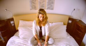 Arbeiten on the go, aber richtig und effizient! Arbeiten on the go: Junge Frau mit langen blonden Haaren sitzt auf dem Bett und tippt am Laptop