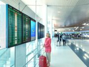 Frauen auf Alleinreisen: Wie fühlen sie sich? Frauen auf Alleinreisen: Eine Frau am Flughafen vor einer Anzeigetafel mit Handgepäck