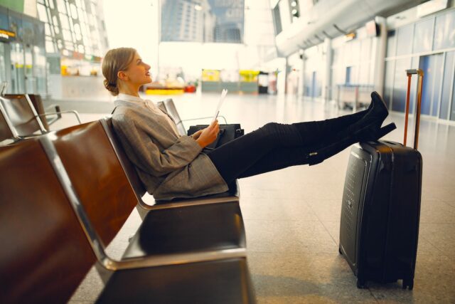 LCC signalisiert Aufwind im Business Travel. Bild, zeigt Frau am Flughafen, die auf ihren Flug wartet