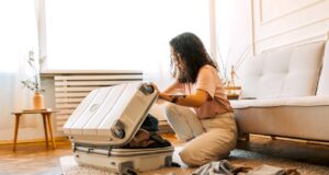 Reiseversicherung: Wann und was zahlt sie? Reiseversicherung: Frau packt Koffer für die Urlaubsreise