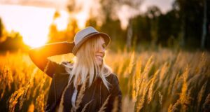 Whitepaper zum besseren Wohlbefinden Whitepaper über das bessere Wohlbefinden. Bild zeigt eine glückliche Frau in einem Feld bei Sonnenuntergang