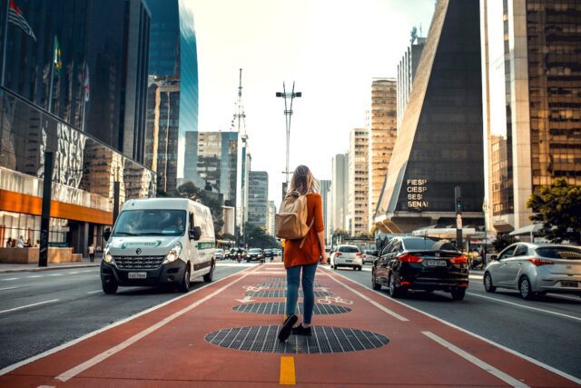 Globale Studie über das Reisen in 2033: Bild zeigt eine Frau mit Rücksack auf einer Fahrbahn in einer Metropole