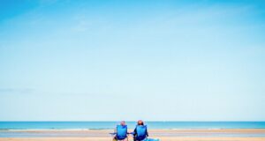 Tipps für eine entspannte Urlaubsreise Tipps für entspannte Urlaubsreisen: Bild zeigt ein Paar am Strand mit Blick zum Meer