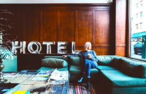 Serviced Apartments sind jetzt angesagt Service Apartments: Bild zeigt eine Frau in einem Hotel. Sie blickt auf die Straße, trinkt Kaffee