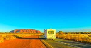 Im Wohnmobil Australiens Ostküste erleben Bis zeigt ein Wohnmobil auf einer Straße zum roten Uluru Ayers Rock im rotem Outbakc von Australien