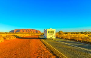 Im Wohnmobil Australiens Ostküste erleben Bis zeigt ein Wohnmobil auf einer Straße zum roten Uluru Ayers Rock im rotem Outbakc von Australien