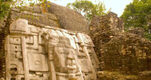 Belize: Reiseziel für Entdecker und Naturfans Bild zeigt eine gut erhaltene Maske eines Maya-Herrschers in Lamanai, Belize, die aus einem Krokodil-Kopfschmuck hervorgeht