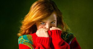 Wovor Frauen auf Reisen sich sehr fürchten Wovor Frauen auf Reisen Angst haben: Bild zeigt eine Frau, die ihren roten Pullover bis zur Nase hochgehoben hat, weil sie sich fürchtet