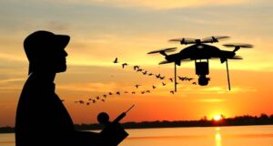 Wenn Drohnen im Urlaub in die Luft gehen Mit einer Drohne im Ausland fotografieren: Bild zeigt einen Mann mit Hut bei Sonnenuntergang, der mit einer Drohne Luftaufnahmen an einem Strand macht