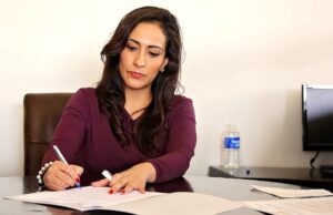 Wie Travel Manager Kosten senken können Wie Travel Manager Kosten senken müssen: Bild zeigt eine Frau, die am Schreibtisch sitzt und etwas aufschreibt