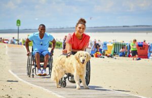 Barrierefrei in Deutschland auf Reisen gehen Barrierefrei reisen: Bild zeigt einen Mann und eine Frau im Rollstuhl mit einem Hund am Strand von Langeoog