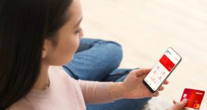 Aircash-App für Maut, Parkgebühr und Bus Mit der Aircash-App für Vignette, Parkgebühr und Transportmittel bezahlen: Bild zeigt eine Frau mit einem Handy und einer Kreditkarte. Auf dem Handy ist d8ie Aircash- App i8nstalliert