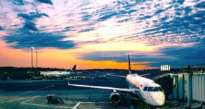 Wet-Leasing: Verstöße gegen Arbeitsrecht? Wet-Leasing: Bild zeigt ein weißes Passagierflugzeug a, Flughafen bei Sonnenuntergang