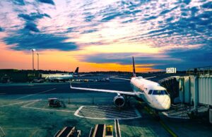 Wet-Leasing: Verstöße gegen Arbeitsrecht? Wet-Leasing: Bild zeigt ein weißes Passagierflugzeug a, Flughafen bei Sonnenuntergang