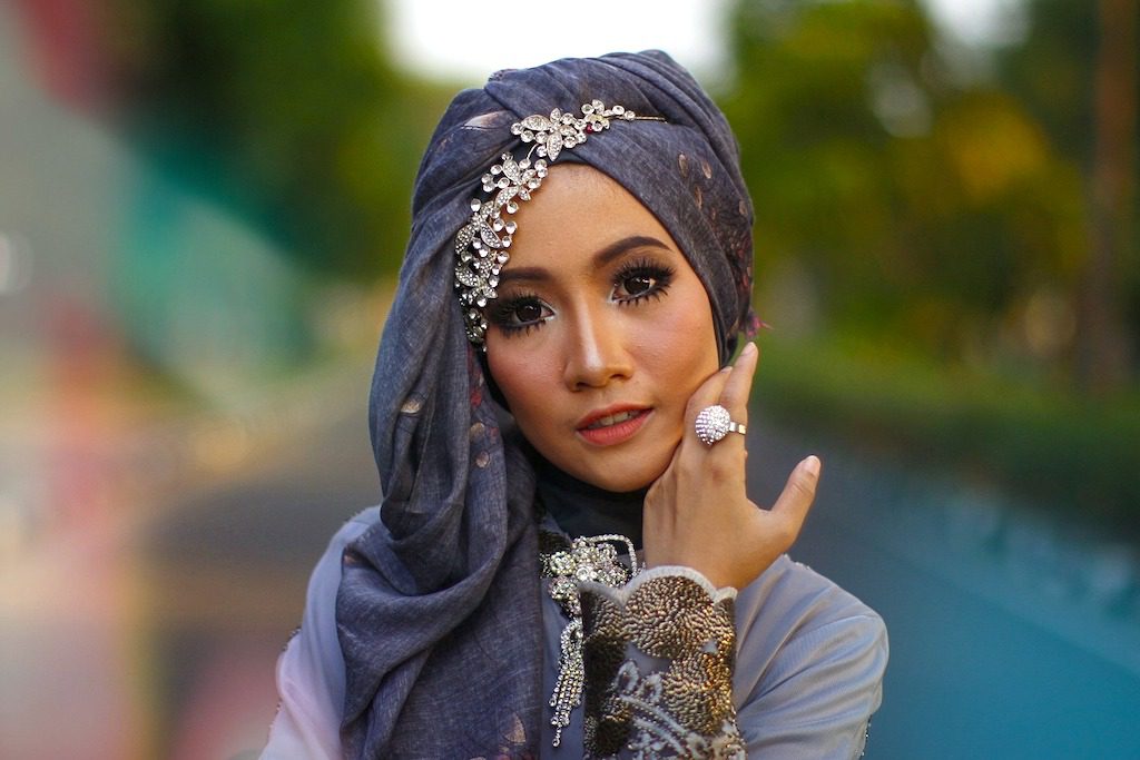 Mode für Muslimas: Bild zeigt eine geschminkte Frau mit einem Kopftuch, das mit Schmuck dekoriert ist