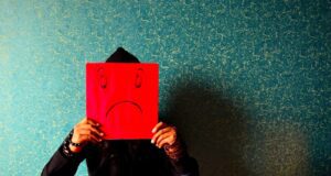 Das brachte Sommerurlauber auf die Palme! Was Sommerurlauber auf die Palme brachte: Bild zeigt am Boden sitzenden Mann mit einem Emoji in den Händen, das Traurigkeit und Ärger darstellt