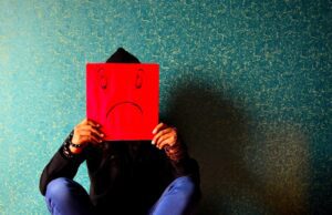 Das brachte Sommerurlauber auf die Palme! Was Sommerurlauber auf die Palme brachte: Bild zeigt am Boden sitzenden Mann mit einem Emoji in den Händen, das Traurigkeit und Ärger darstellt