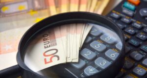Wie Taggelder einfach abgerechnet werden Taggelder einfacher abrechnen: Bild zeigt unter einer Lupe mehrere Euro-Scheine und einen Taschenrechner