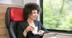 AIRail hebt jetzt im 30 Minuten-Takt ab AIRail im 30-Minutentakt. AIRail verbindet die Stadtzentren von Linz, Salzburg und Graz mit dem Flughafen Wien. Bild zeigt eine Frau mit Kaffeetasse in einem Zugabteil