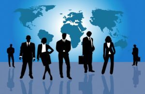 Mehrwert für Firmen durch Geschäftsreisen Mehrwert für Unternehmen durch Geschäftsreisen. Bild zeigt Menschengruppe vor einem blauen Hintergrund mit der Weltkarte