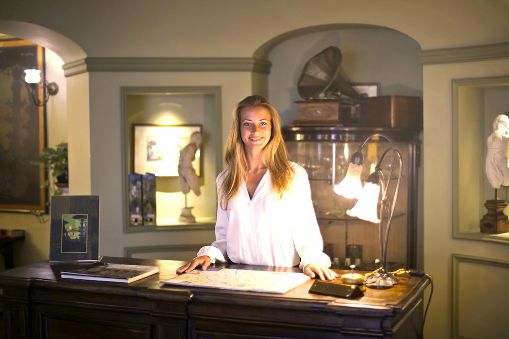 Aufbruch in der globalen Hospitality-Branche: Bild zeigt Hotelrezeption mit einer jungten Frau hinter dem Desk bei Beleuchtung