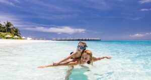 Sonne tanken, wenn andere zuhause frieren Sonne tanken im Winterurlaub: Frau mit kleinem Mädchen plantscht am Strand im türkisfarbenen Meer des Indischen Ozeans