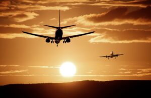 Wie gehen Airlines mit Beschwerden um? Welche Airlines zuverlässig sin d und welche weniger: Zwei Flugzeuge fliegen im Sonnenuntergang am Himmel