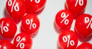 So verbilligen Rabatte und Boni den Urlaub! Rote Luftballons mit dem Prozentsymbol symbolisieren Rabatte und Boni