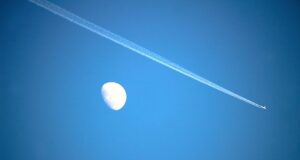 Flugrouten-Technologie für saubere Flüge Innovative Flugrouten-Technologie: Bild zeigt am blauen Himmel den Mond und einen vorbeifliegenden Jet mit einem breiten Kondensstreifen
