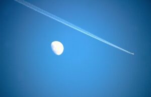 Flugrouten-Technologie für saubere Flüge Innovative Flugrouten-Technologie: Bild zeigt am blauen Himmel den Mond und einen vorbeifliegenden Jet mit einem breiten Kondensstreifen