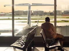 Kein Ärgernis, keine Ausgleichsleistung! Mann sitzt in der Wartehalle eines Flughafens und blickt hinaus aufs Rollfeld, wo ein Flugzeug steht