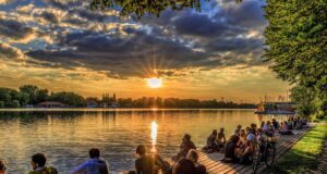 Hannover unter den Top 10 der Städteziele Romantischer Sonnenuntergang am Maschsee in Hannover , Menschen sitzen am Ufer und beobachten den Sonnenuntergang