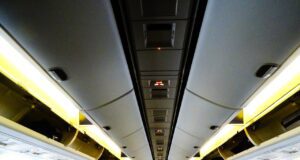Clever buchen und bei Flugreisen sparen Clever buchen: Innenraum eines Passagierflugzeugs mit Blick zum Cockpit in gelblicher Beleuchtung