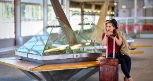 Zu späte Gepäckaufgabe: Keine Rückzahlung Gepäckaufgabe: Frau mit roten Stöckelschuhen sitzt aufgestützt auf ihren Trollen in einer Wartehalle am Flughafen