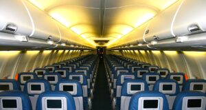 Welcher Sitzplatz im Flugzeug ist sicher? Sitzplatz im Flugzeug: Gelblich beleuchteter Kabinenraum mit leeren Sitzreihen in einem Flugzeug