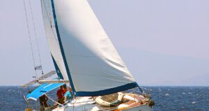 Trotz Bootsführerschein: Stress im Urlaub? Bootsführershein: Leicht zur Seite geneigtes weißes Segelschiff mit aufgeblähtem Segel unterwegs auf dunkelblauem Meer