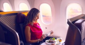 LATAM Airlines siegt mit Kulinarik an Bord Latam Airlines: Frau sitzen in einem Flugzeug, vor ihr auf dem Klapptisch mehrere Speisen und Getränke