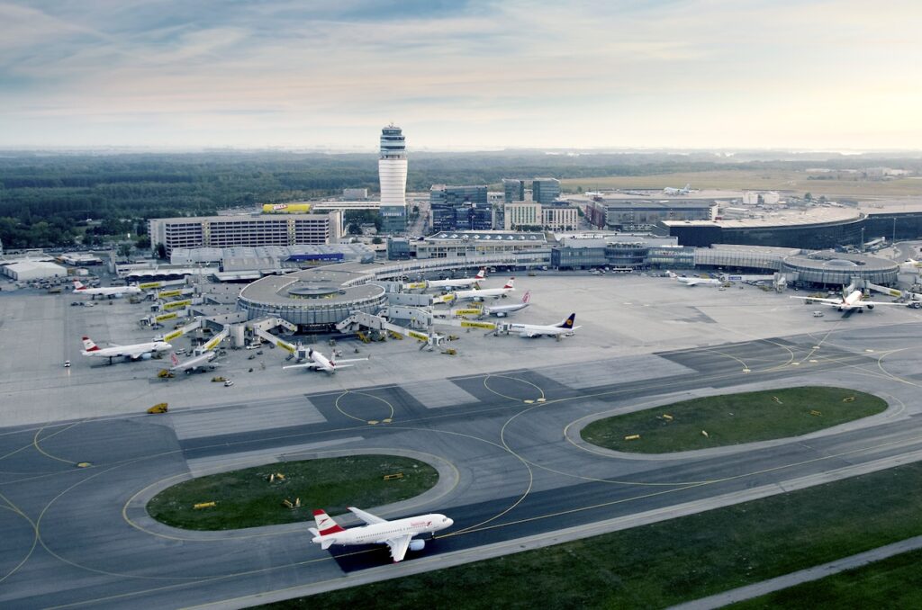 Luftaufnahme vom Flughafen wien mit tower und zahlreichen Passagierflugzeugen an den Gates