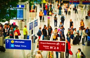 Wer verzichtet eher auf Flug in den Urlaub? Flughafen in Deutschland mit vielen Reisenden, die sich beim Check-in anstellen