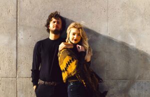 Gen Z reist völlig anders als Baby Boomer Gen Z reist anders als Baby Boomer: Junger Mann in einem Pullover mit junger blonden Frau mit ockergelbbunten Umhang lehnt an einer Wand. Das Paar wirft einen Schatten auf die Wand