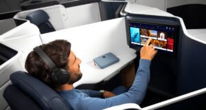 Air France: Business Class zum Wohlfühlen Mann sitzt in der Business Class von Air France und tippt mit dem Finger auf einen Bildschirm vor ihm, der auf der Rückseite des Vordersitzes integriert ist